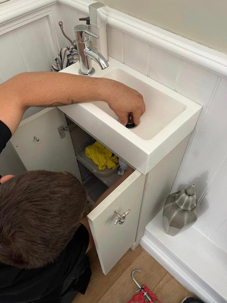Plumber fixing waste pipes beneath a basin – hands-on plumbing service in Sunderland. plumber in North East England