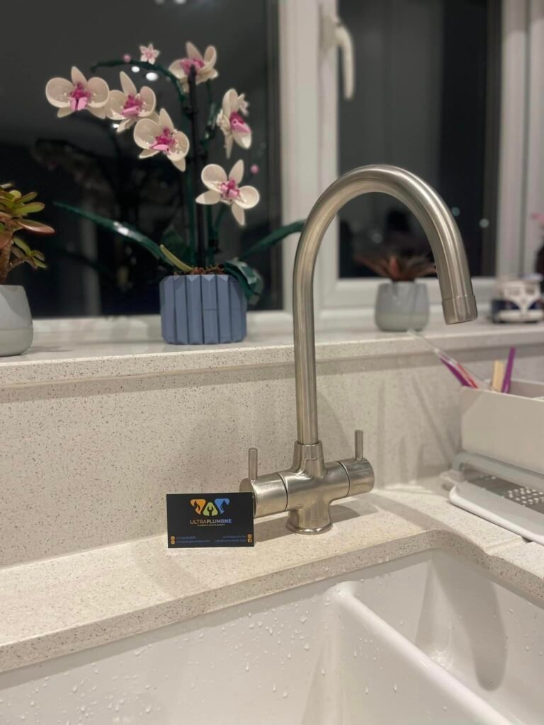 Modern chrome kitchen tap with Ultra Plumb & Gas NE business card – expert plumbing and heating in Sunderland for kitchens and home renovations.
